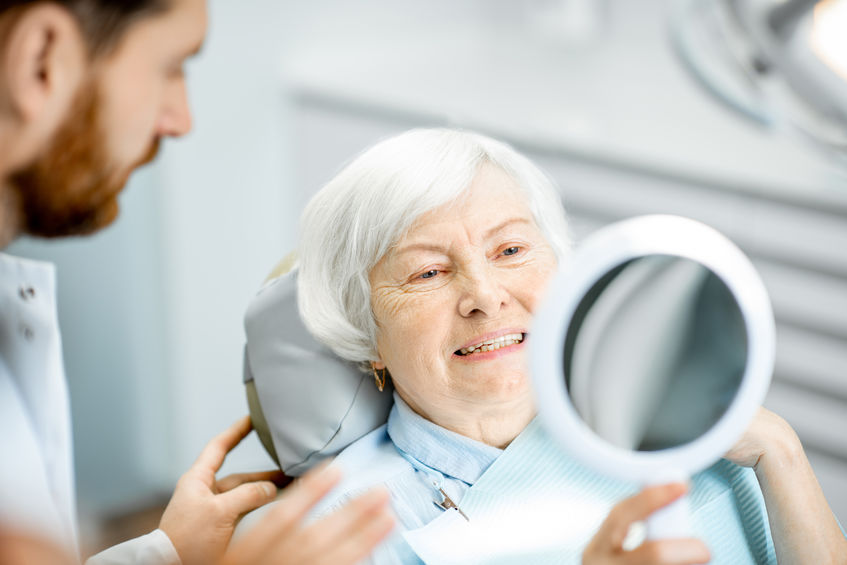 Older woman smiling at dentist office after procedure