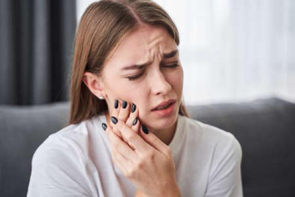 A woman holds her jaw in pain
